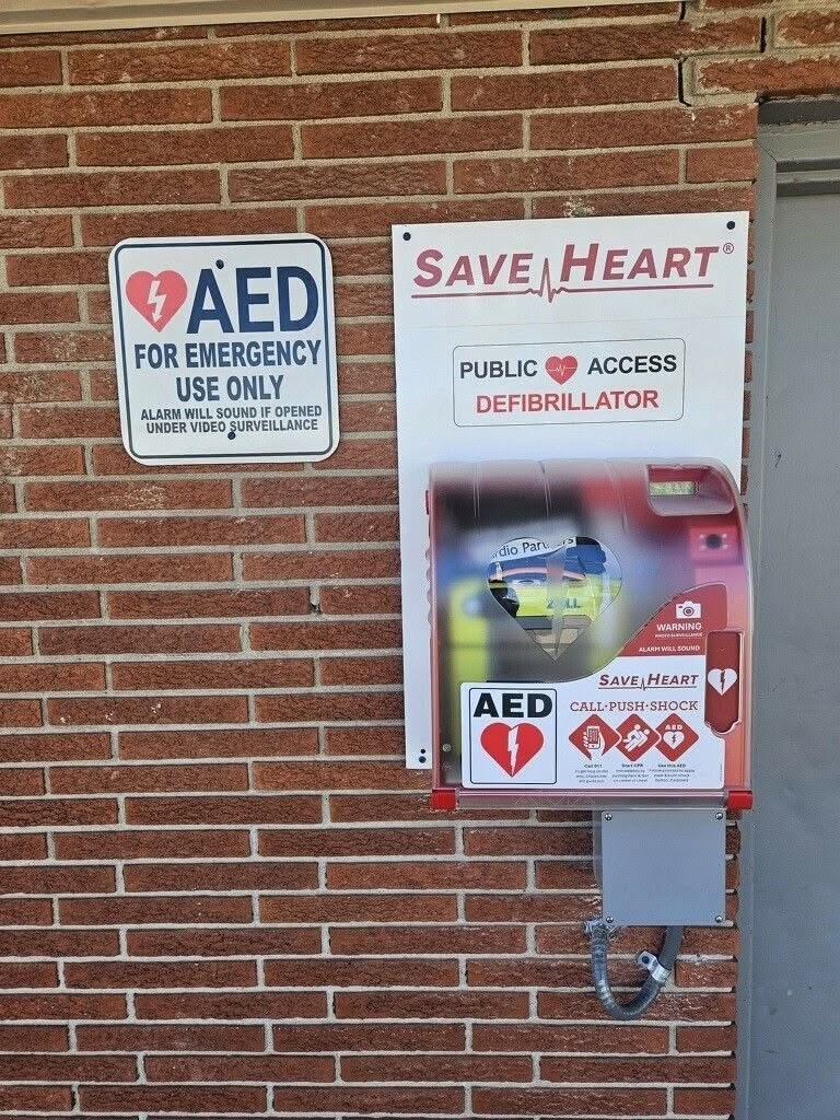 SaveHeart by HeartNation Wall-Mount AED cabinet with a Public Access Defibrillator sign on a brick building in Wyandotte